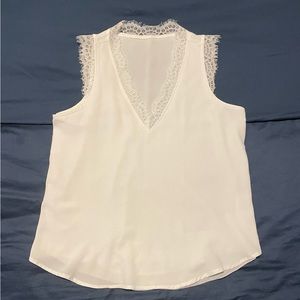White sleeveless blouse with lace detail at neckline/arms
